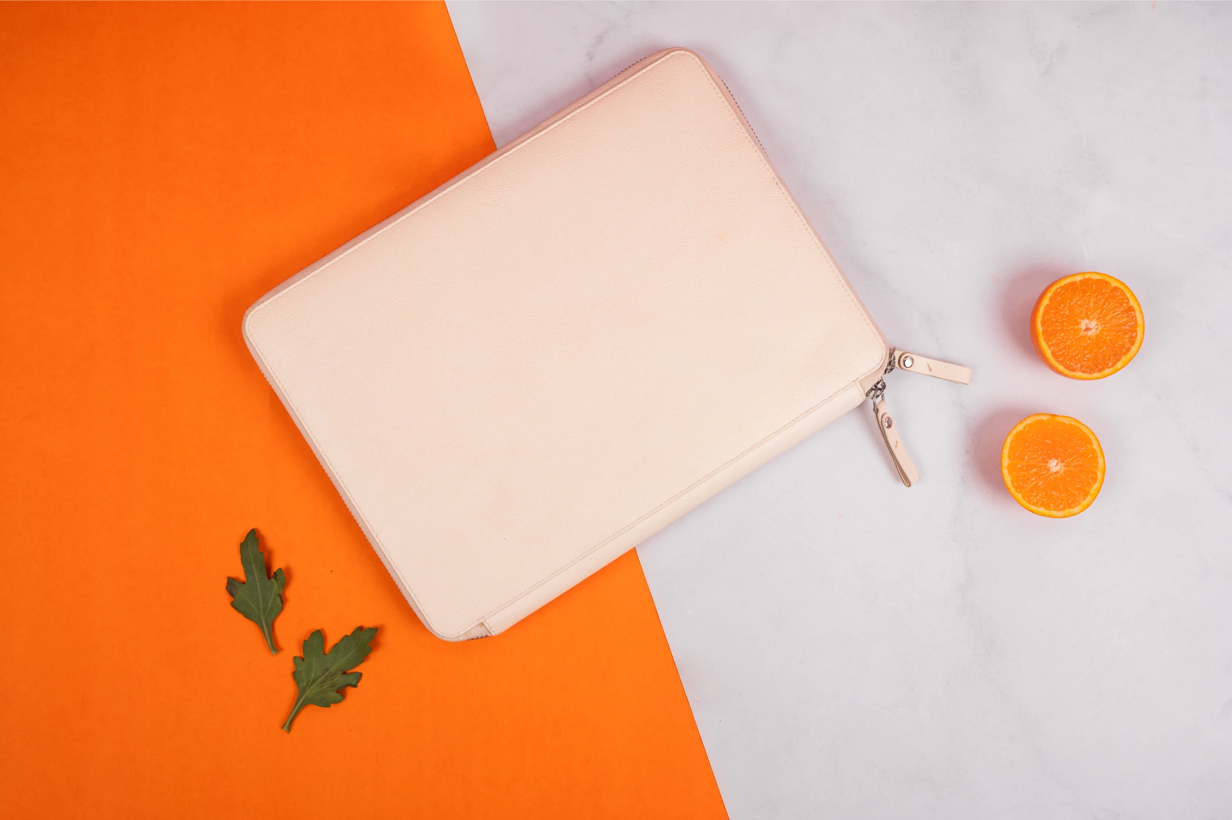 Beige vegan leather pouch with a zipper on an orange and gray background