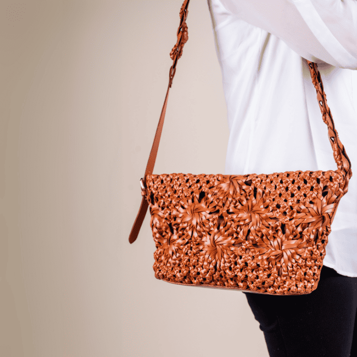 Brown woven leather handbag for women with a textured pattern held by a person wearing a white shirt.