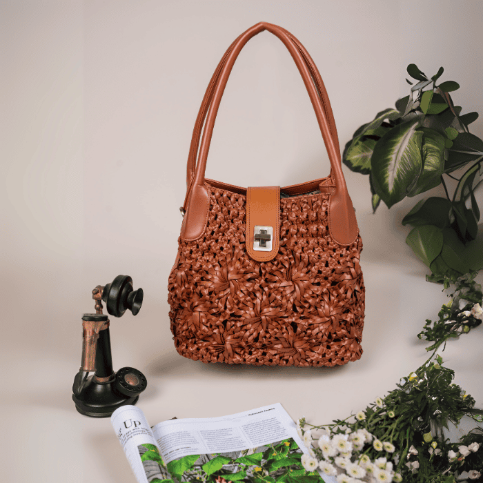 Brown textured vegan leather handbag for women on a surface with a plant and vintage phone in the background