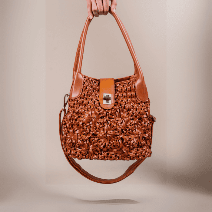 Brown textured vegan leather handbag for women held by a hand against a beige background