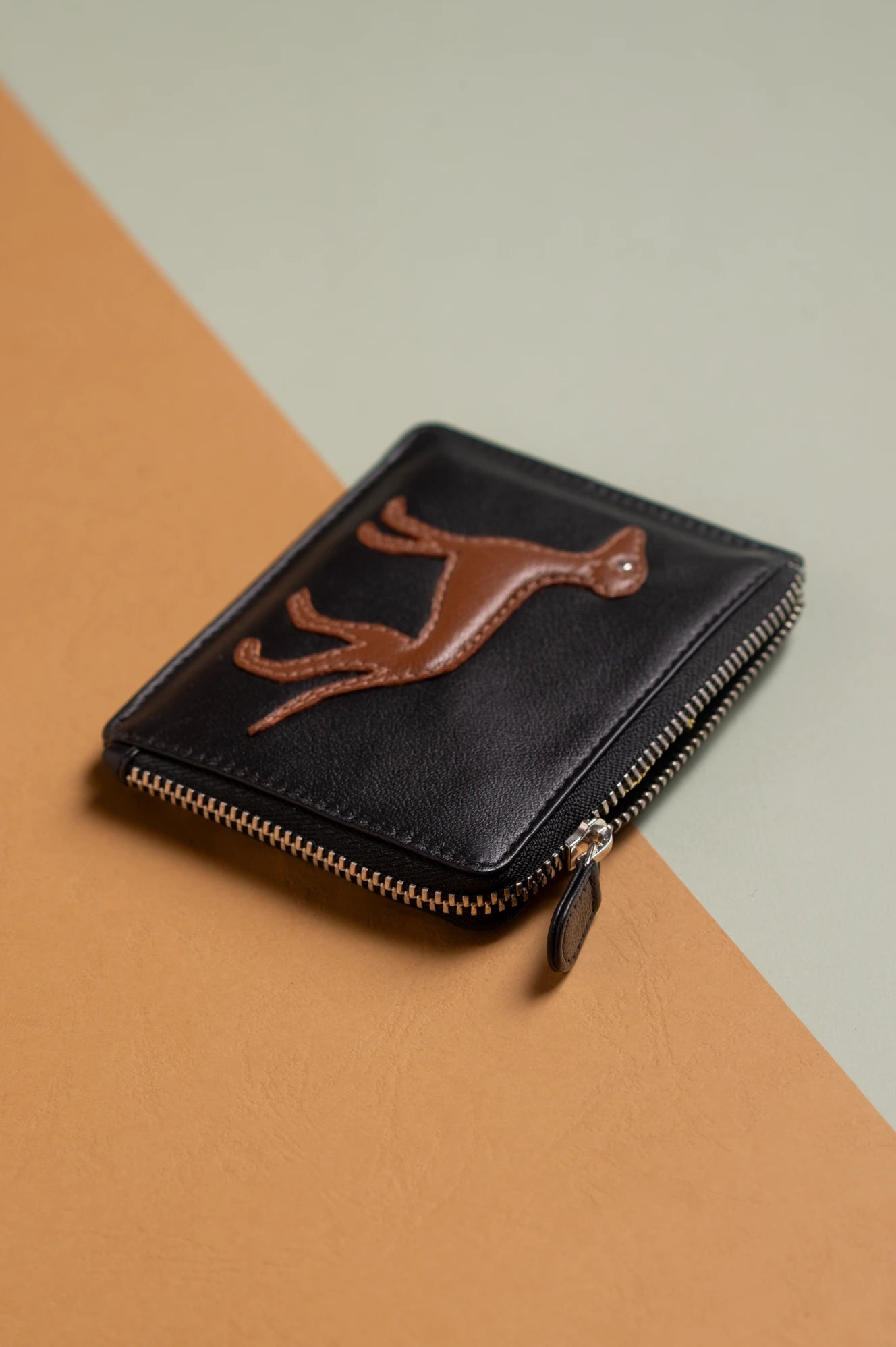 Black vegan leather wallet for women with brown deer emblem on a two-tone background