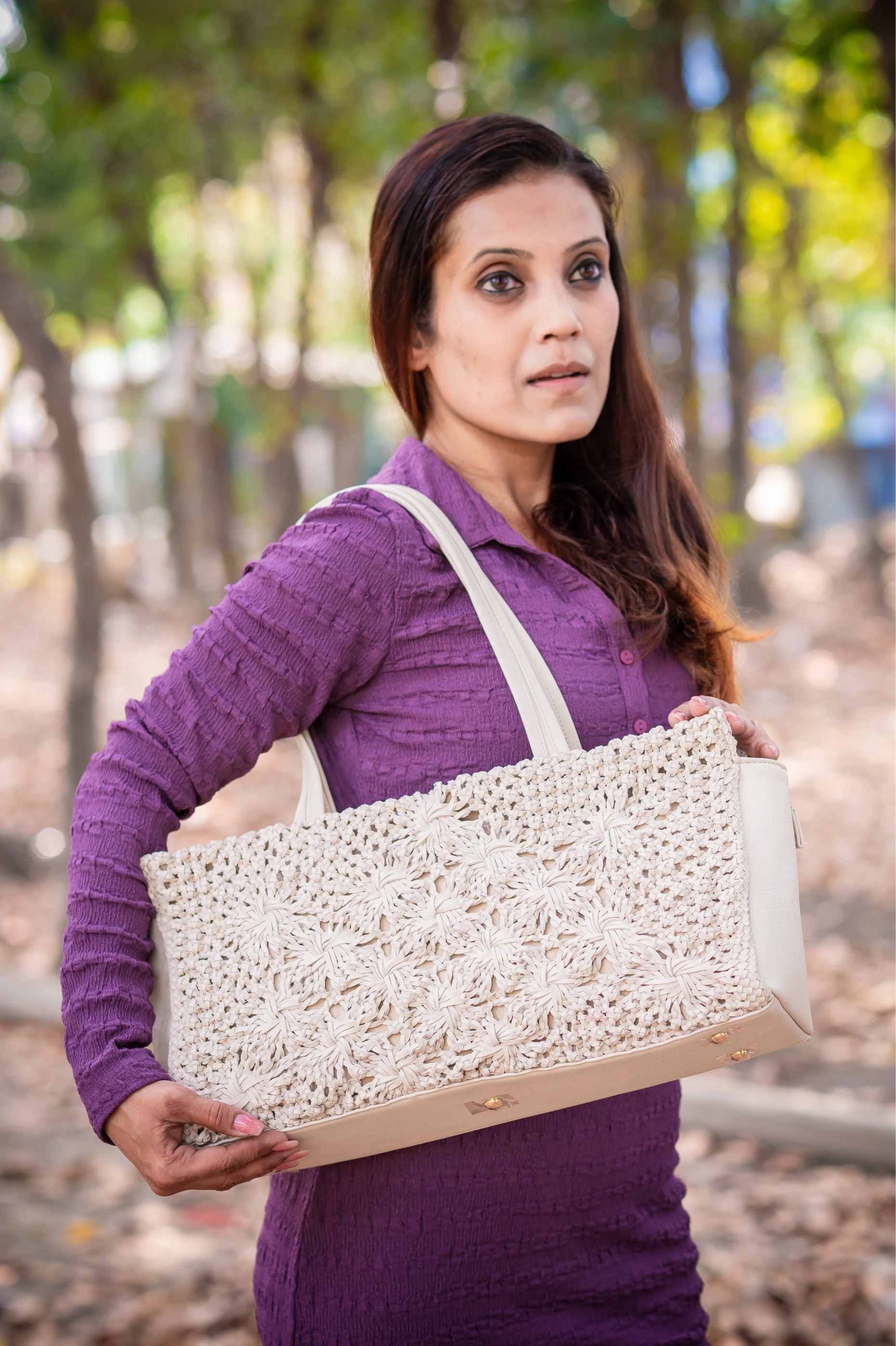 Woman holding a white textured vegan leather handbag for women outdoors with trees in the background