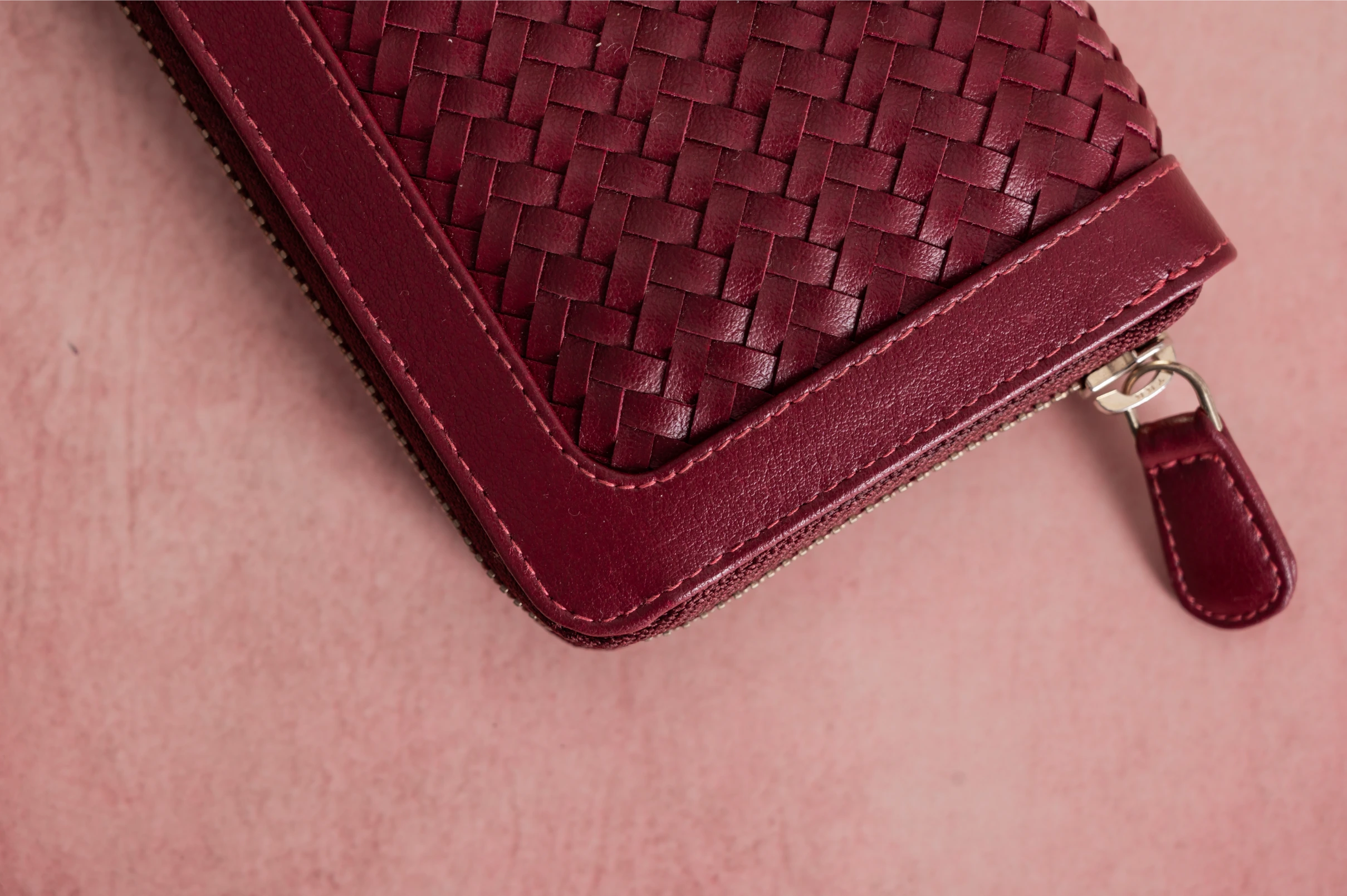 Close-up of a maroon woven Vegan Leather Wallet for women on a matching pink background