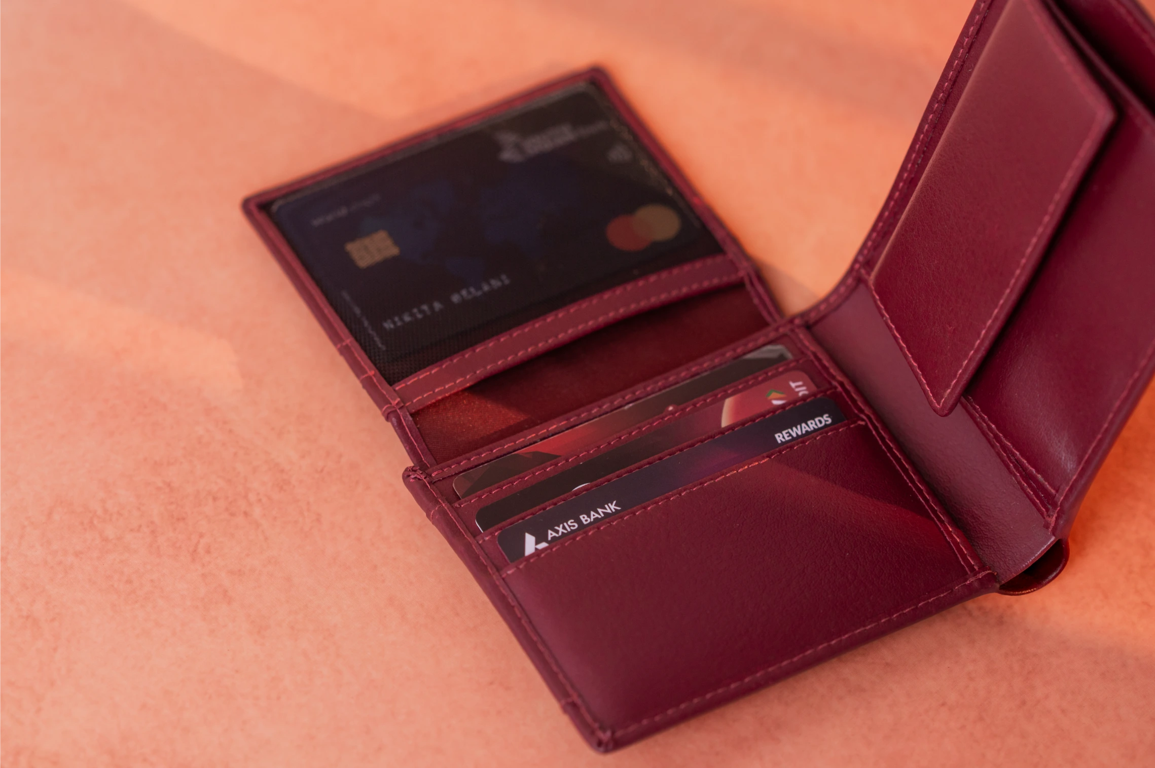 Open burgundy vegan leather wallet for men with cards on a matching background