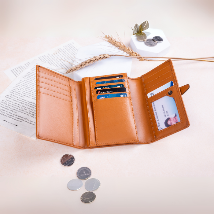 Open brown vegan leather wallet with cards and coins on a light surface