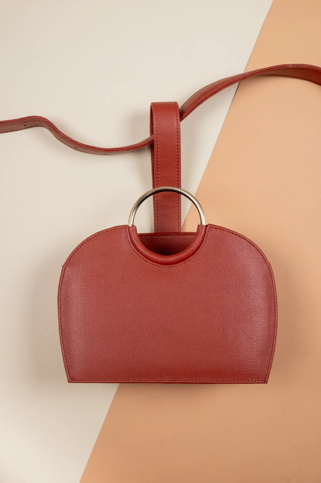 Red vegan leather handbag for women with a ring handle on a beige background