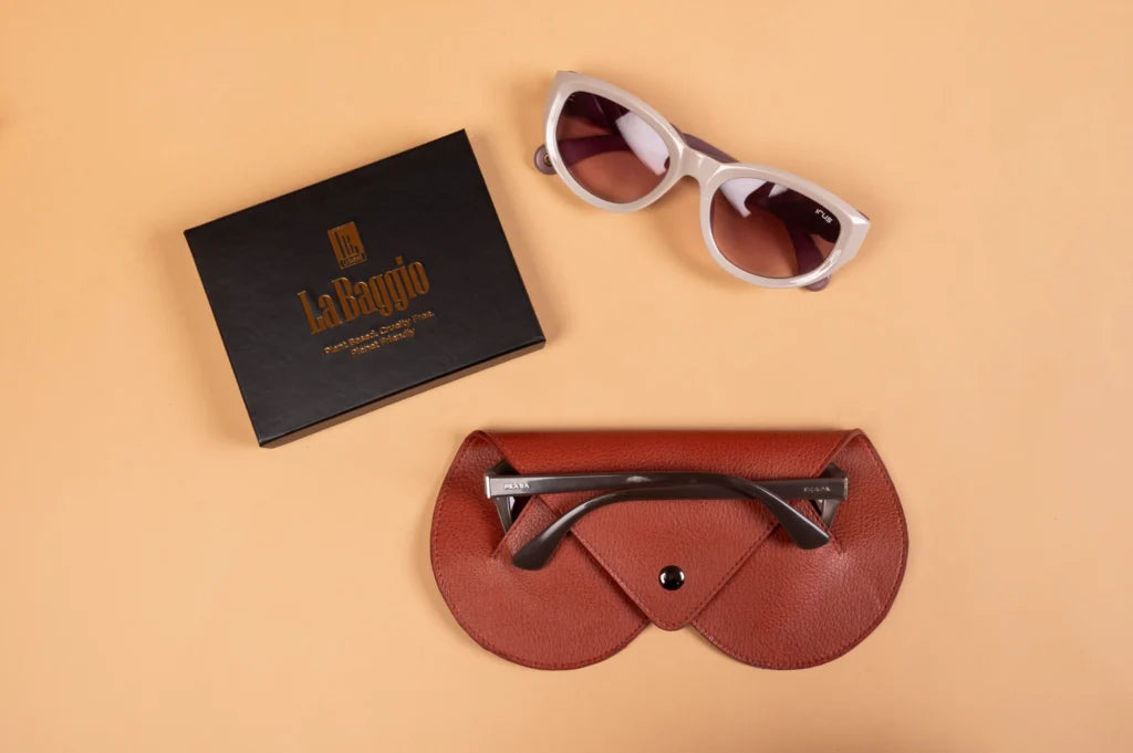 Sunglasses with a brown vegan leather case and La Baggio box on a beige background