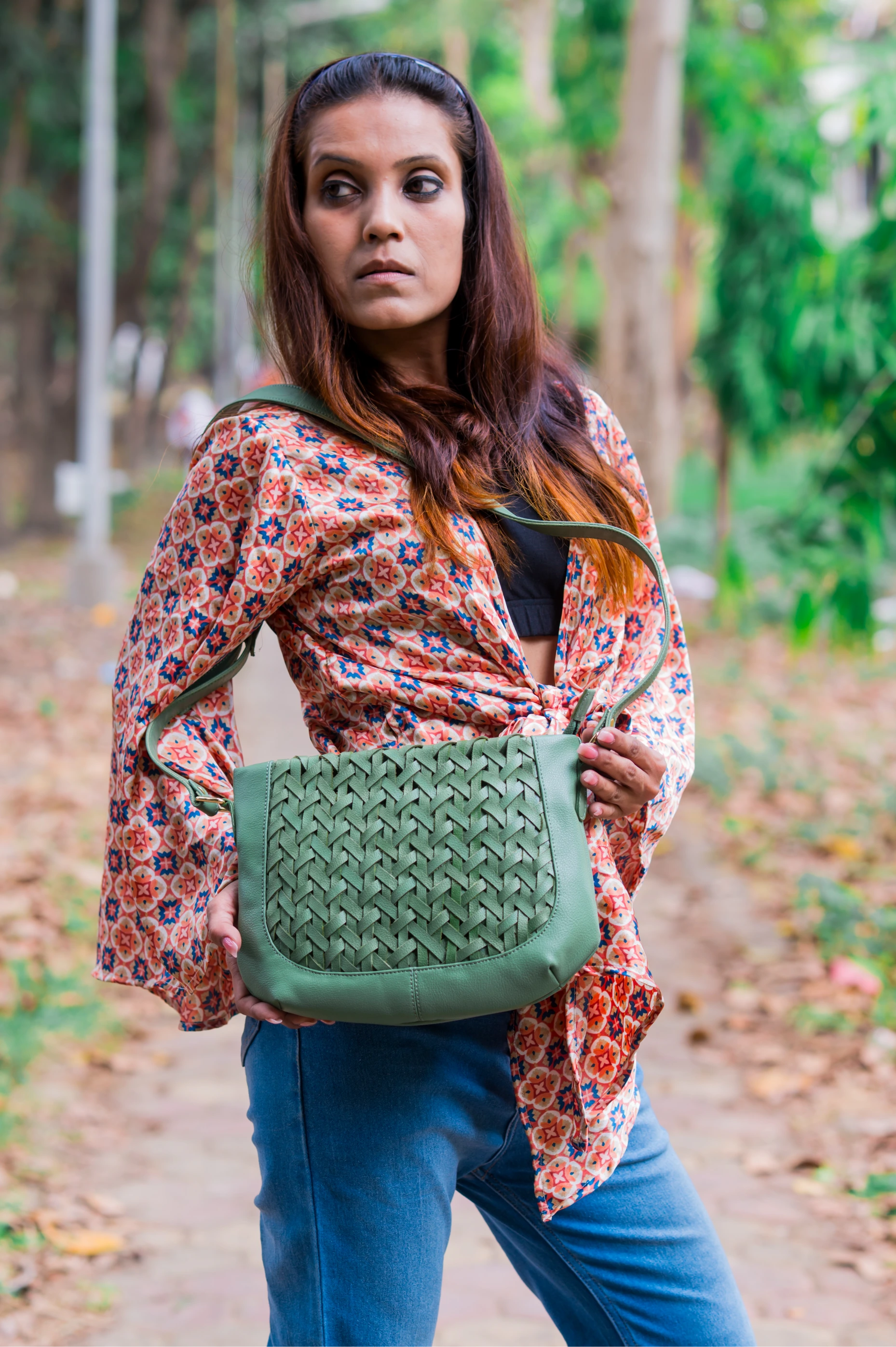 Woman holding a green woven vegan leather bag for women outdoors in a natural setting