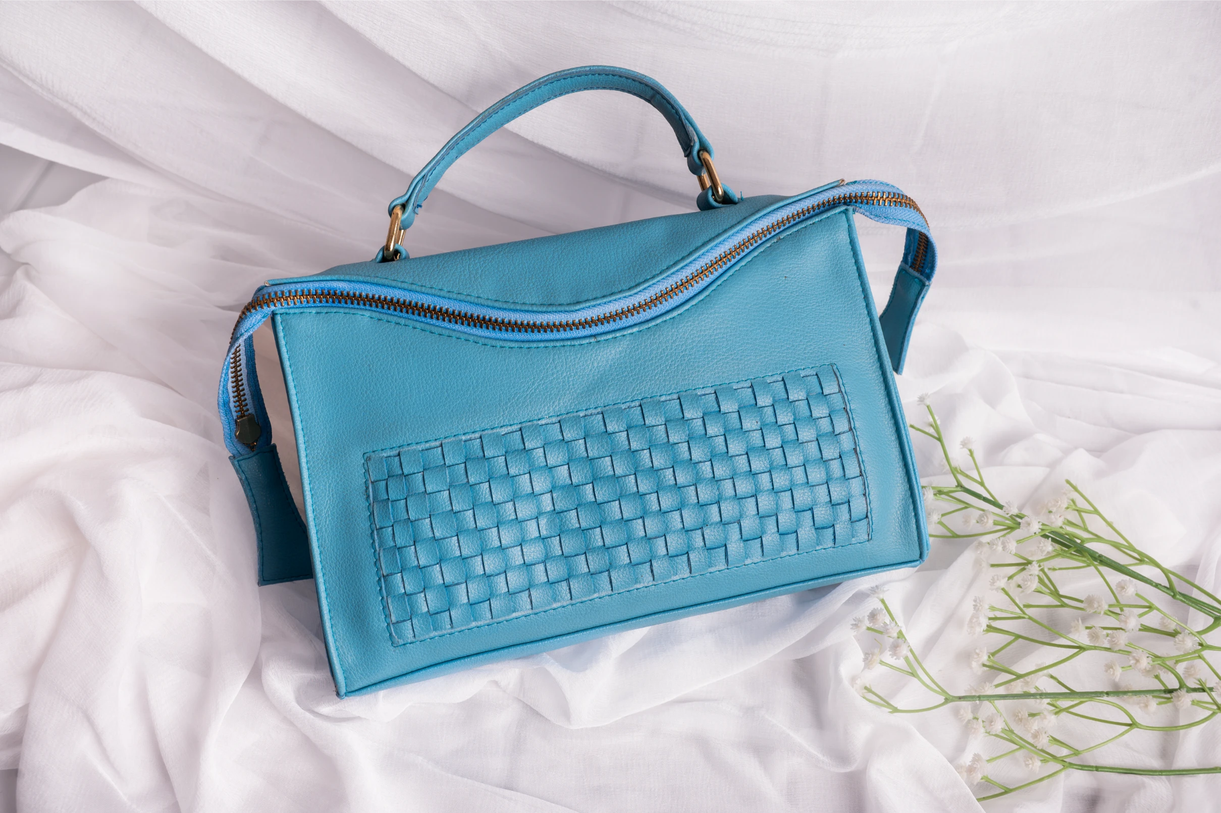 Blue vegan leather handbag for women with woven pattern on a white background