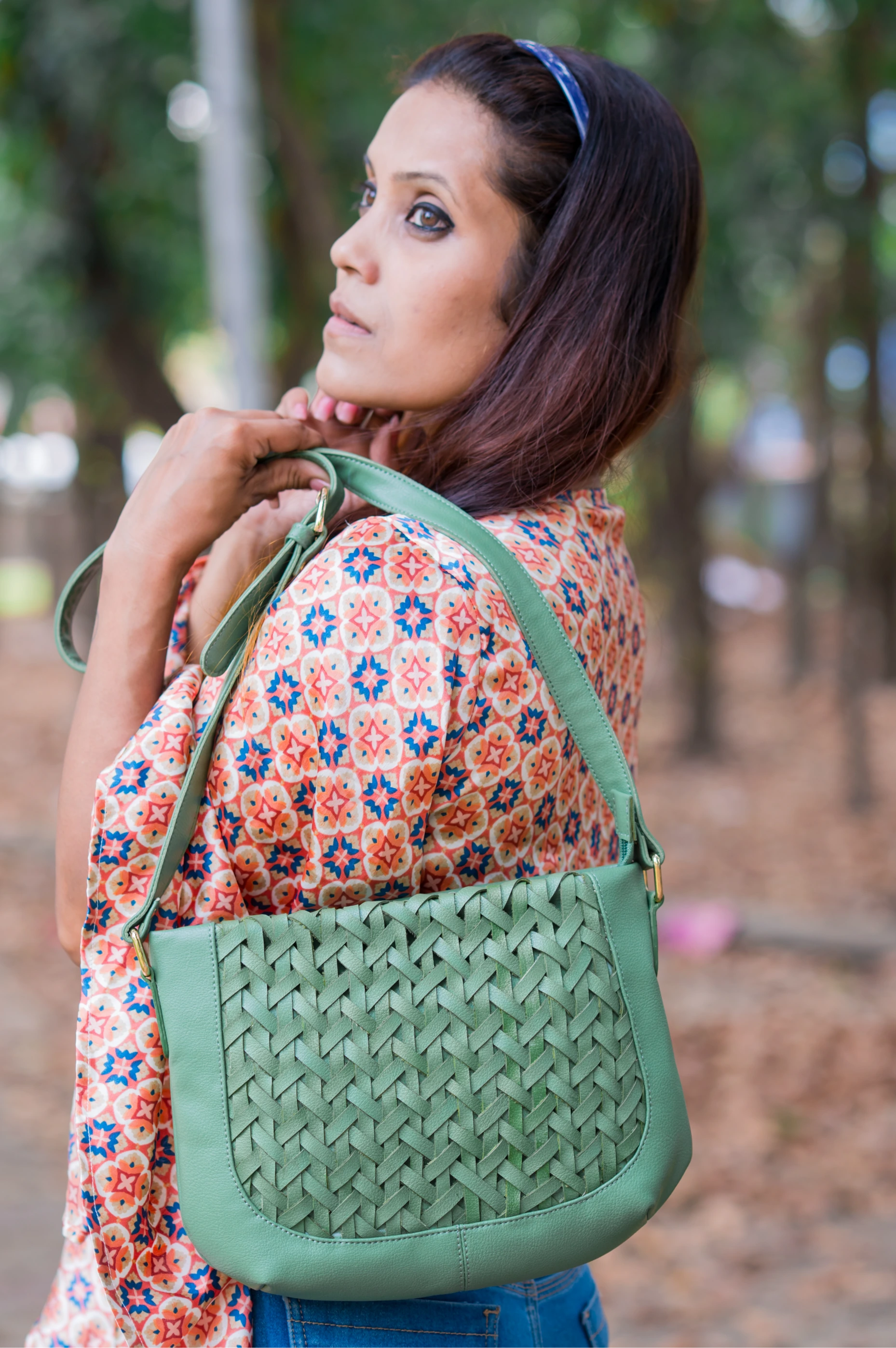 Woman holding a green woven vegan leather handbag for women outdoors