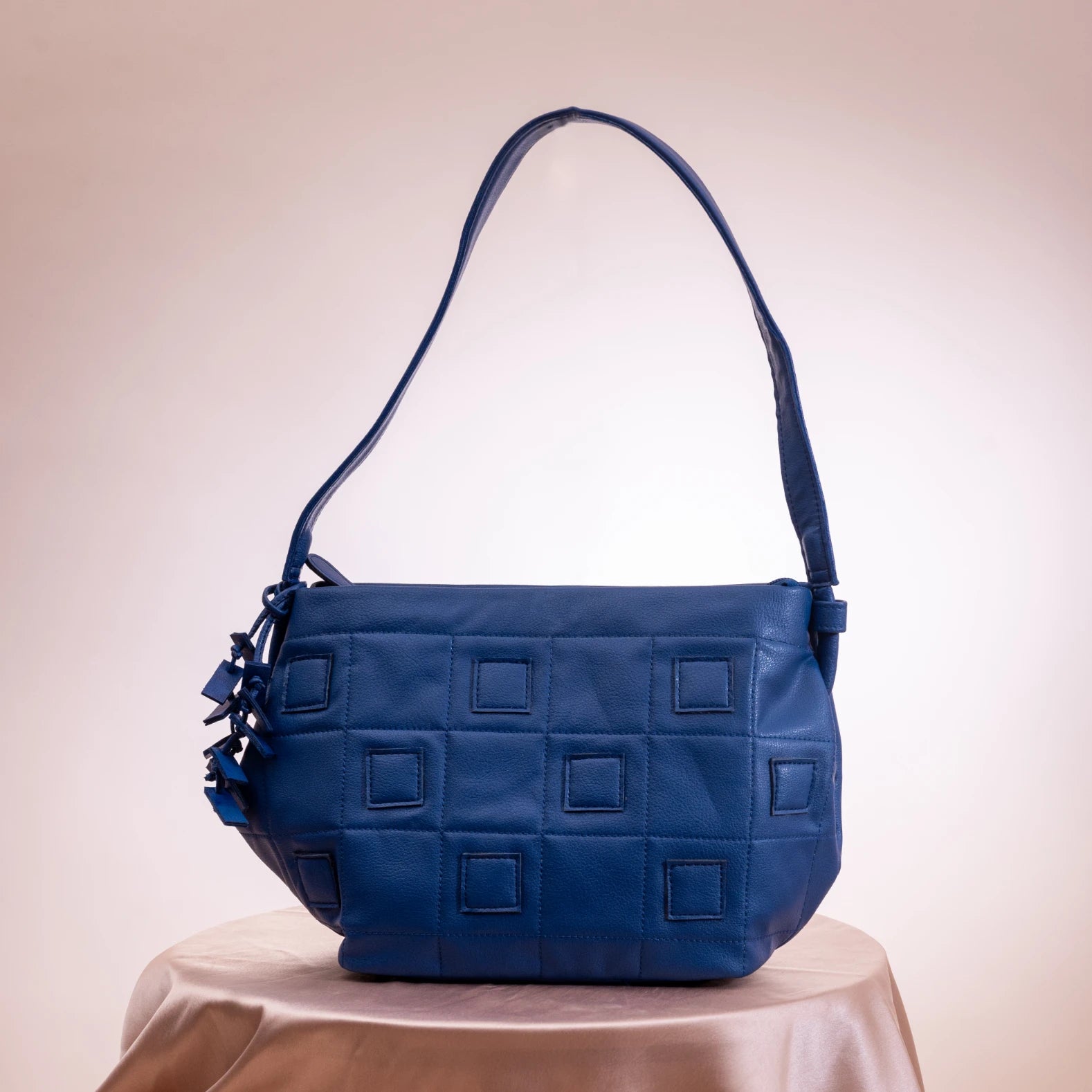 Blue quilted vegan handbag for women on a white surface with a beige background