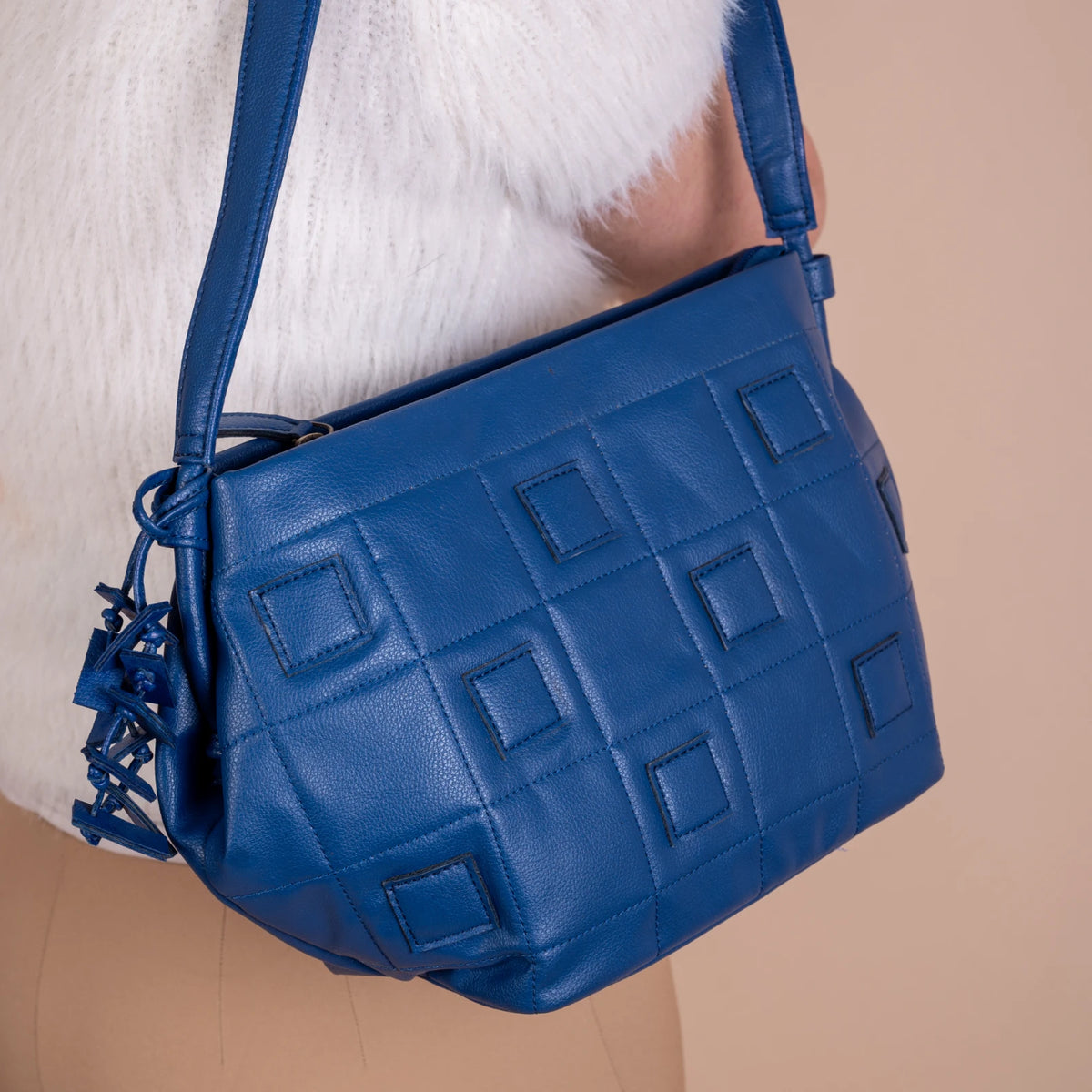 Blue textured vegan leather handbag for women held by a person wearing a white sweater.