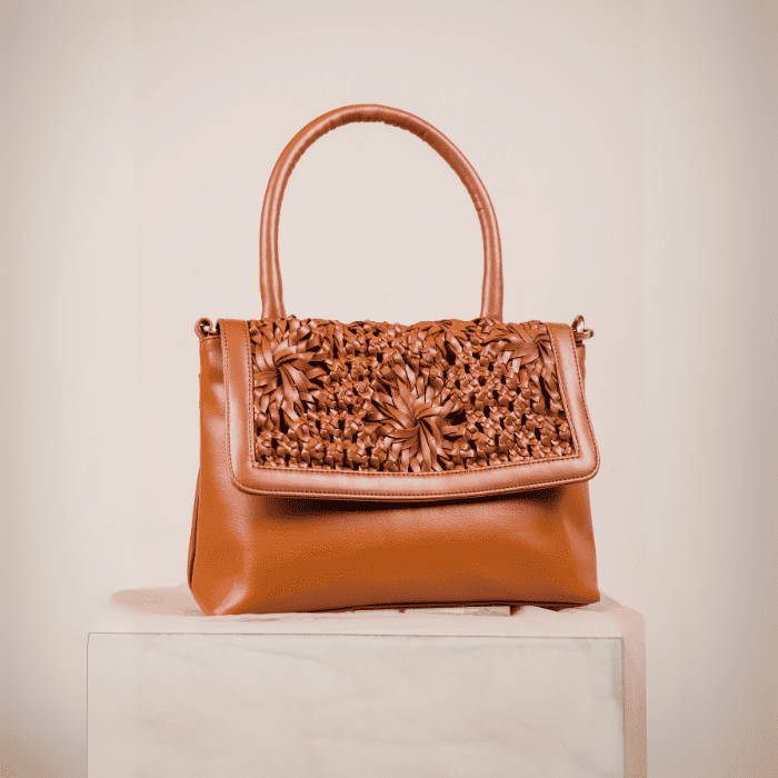 Brown vegan leather handbag for women with intricate floral patterns on a beige background