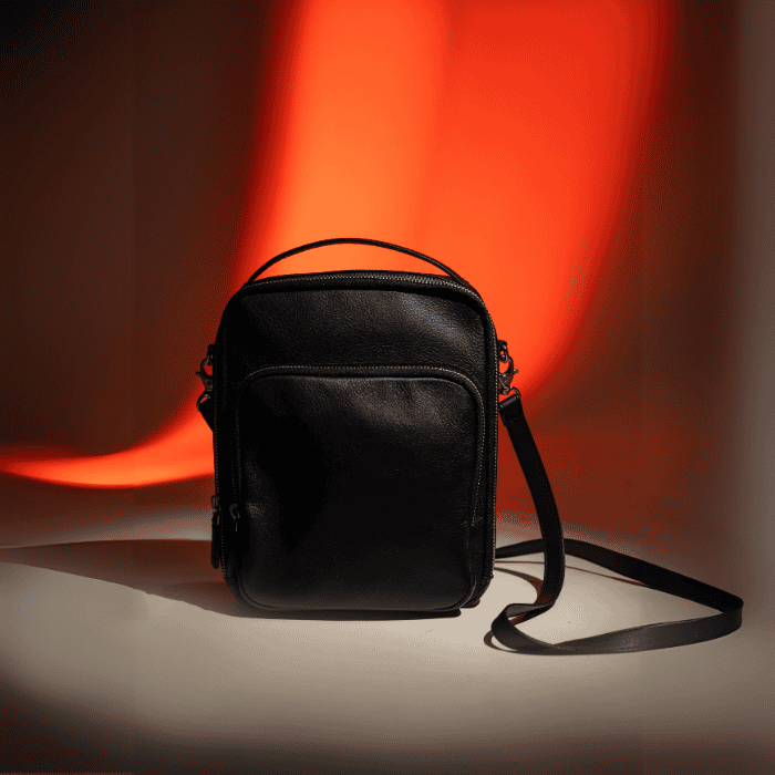 Black vegan leather bag with a strap on a dark background