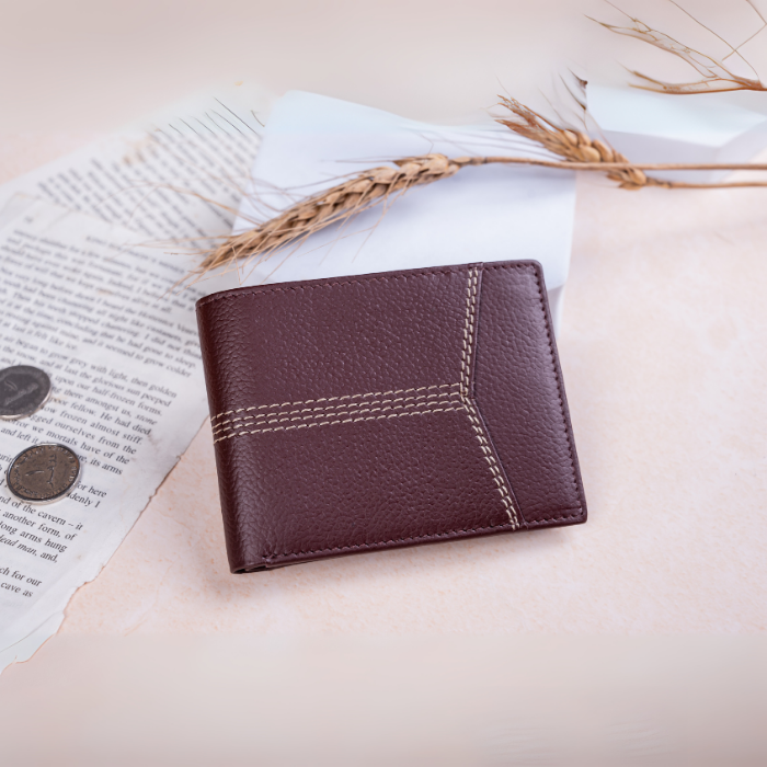 Brown vegan leather wallet for men on a light surface with an open book and wheat stalks.