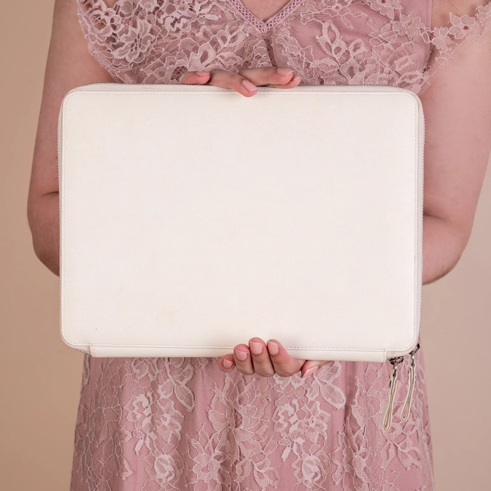 Person holding a white vegan leather clutch bag for women against a beige background