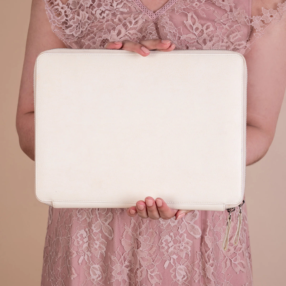 Person holding a white vegan leather clutch bag for women against a beige background
