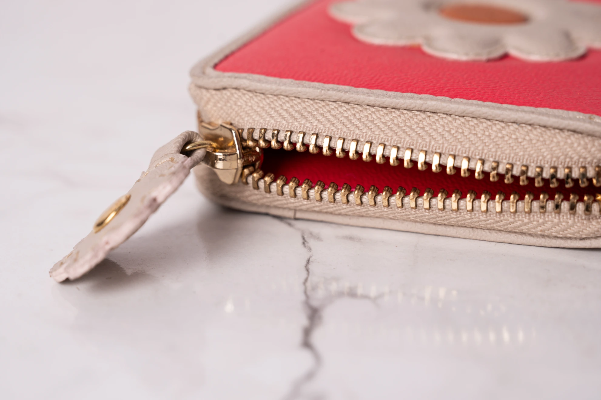Close-up of a pink vegan leather wallet for women with a gold zipper on a marble surface