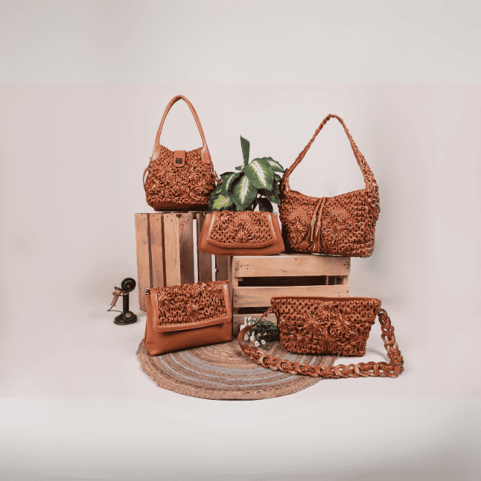 Collection of brown woven vegan leather handbags for women and a clutch on a wooden crate with a neutral background