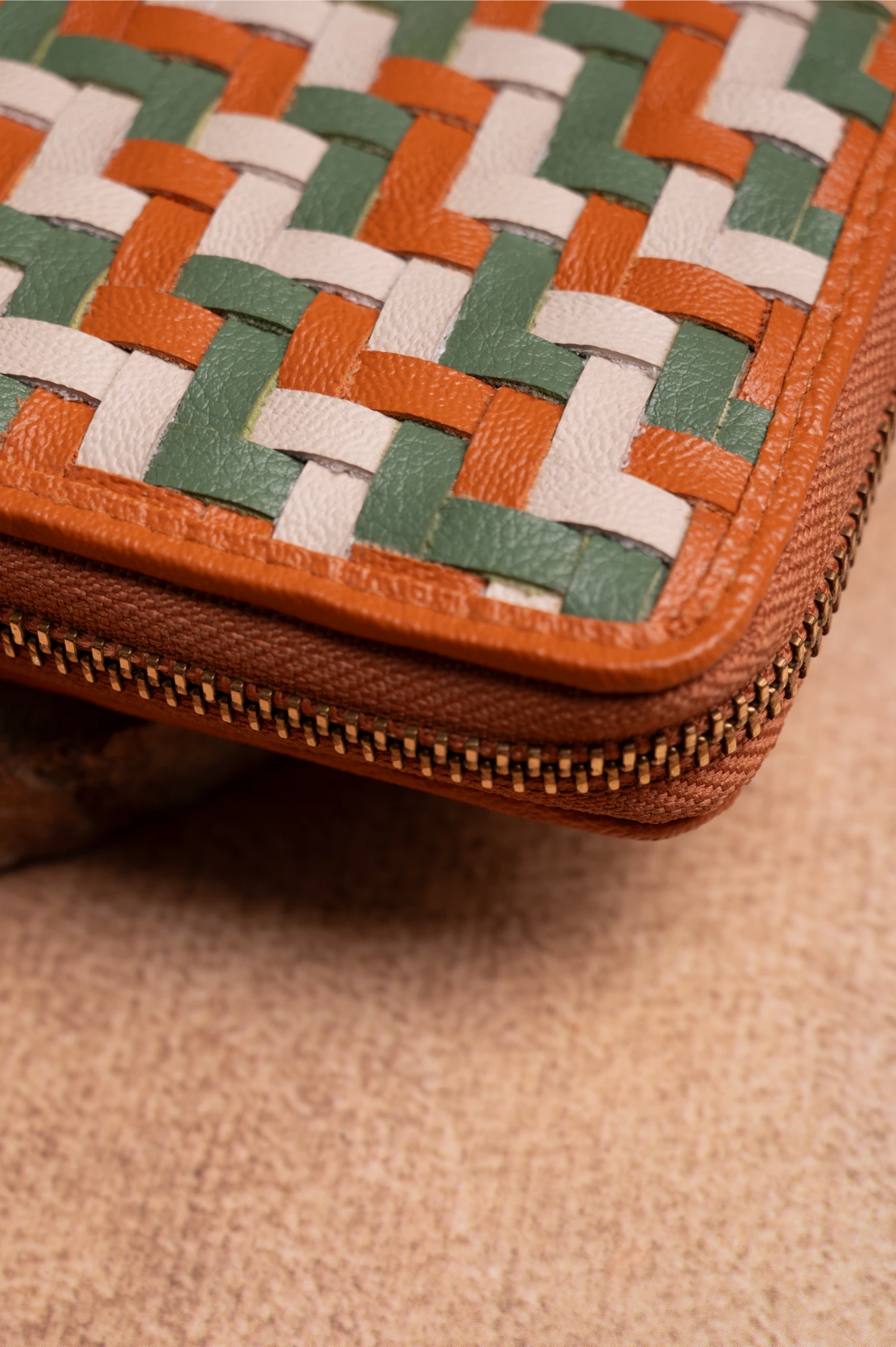 Close-up of a woven vegan leather wallet for women with a zipper on a beige surface