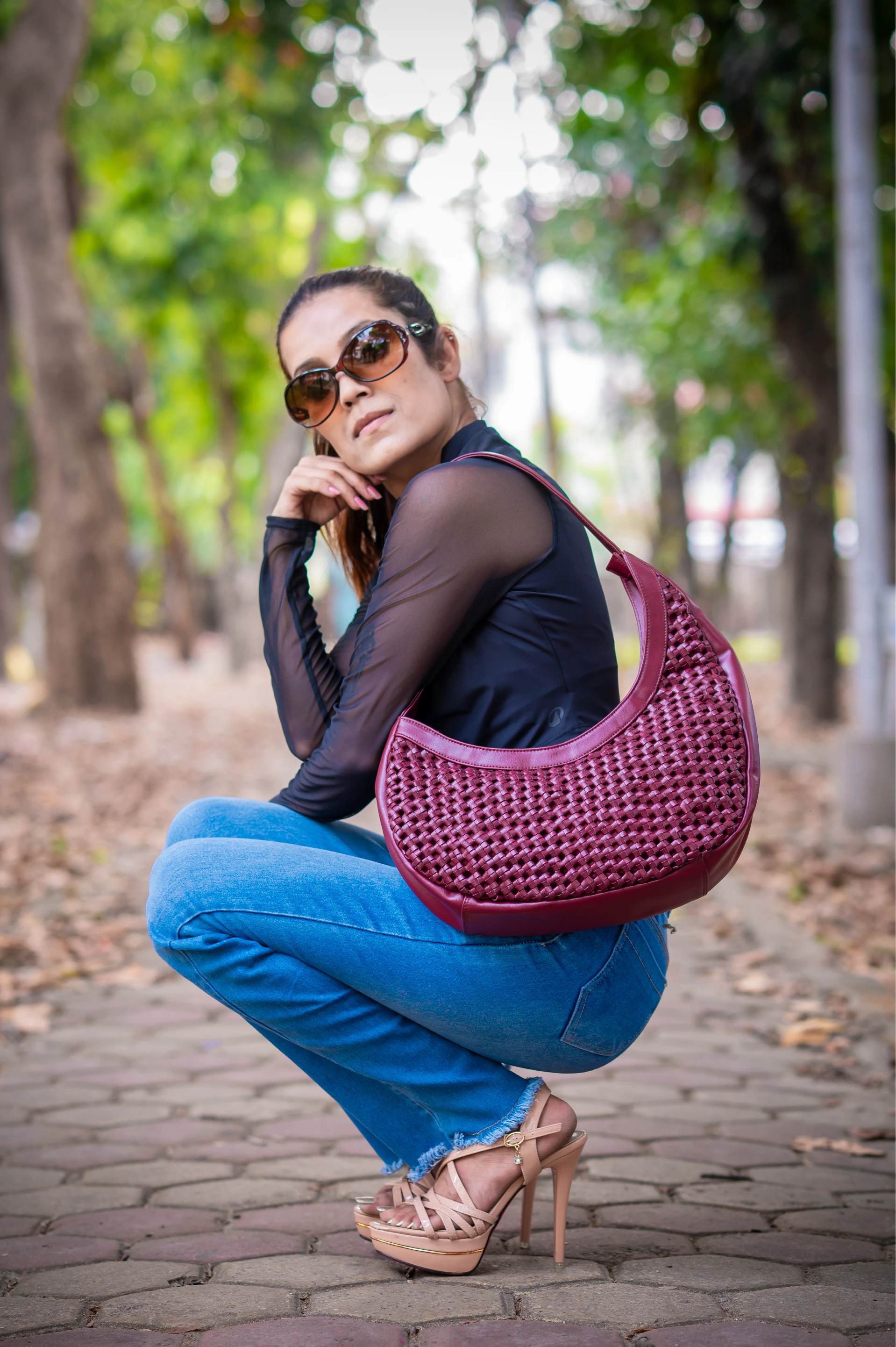 Woman squatting outdoors holding a purple vegan leather handbag for women