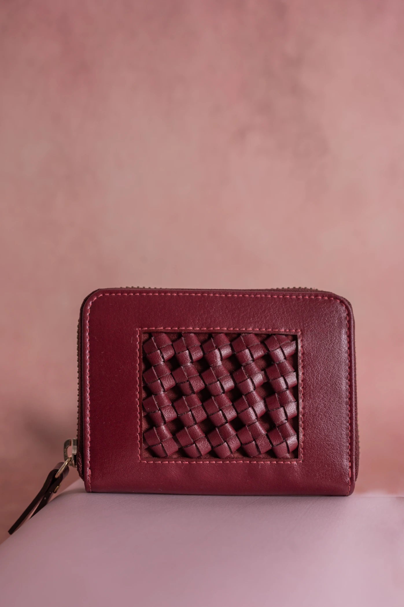 Maroon vegan leather wallet for women with woven design on a pink background