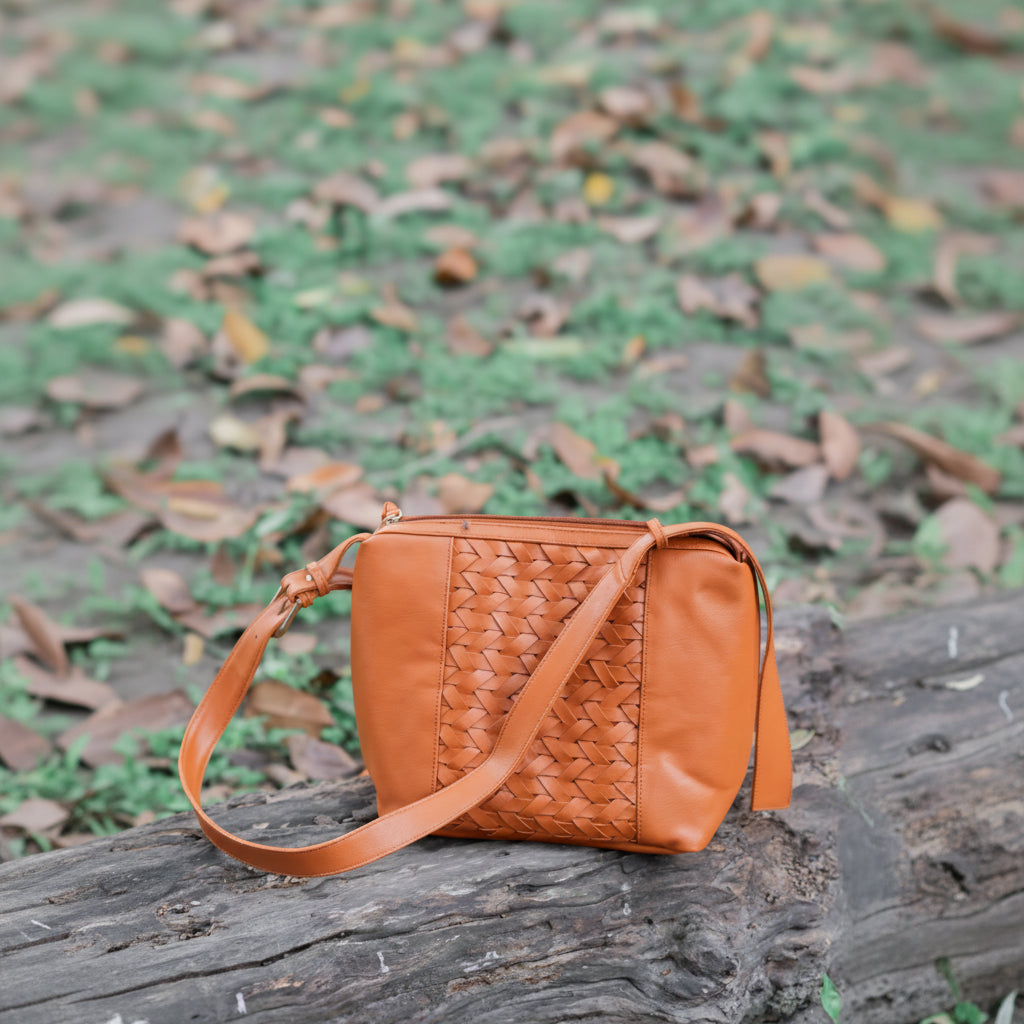 Brown woven vegan leather handbag for women on a textured surface with a blurred natural background