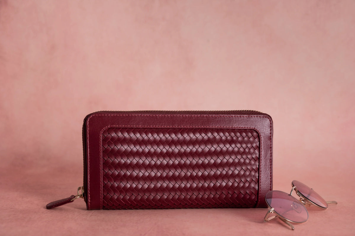 Maroon woven Vegan Leather Wallet for women with sunglasses on a pink background