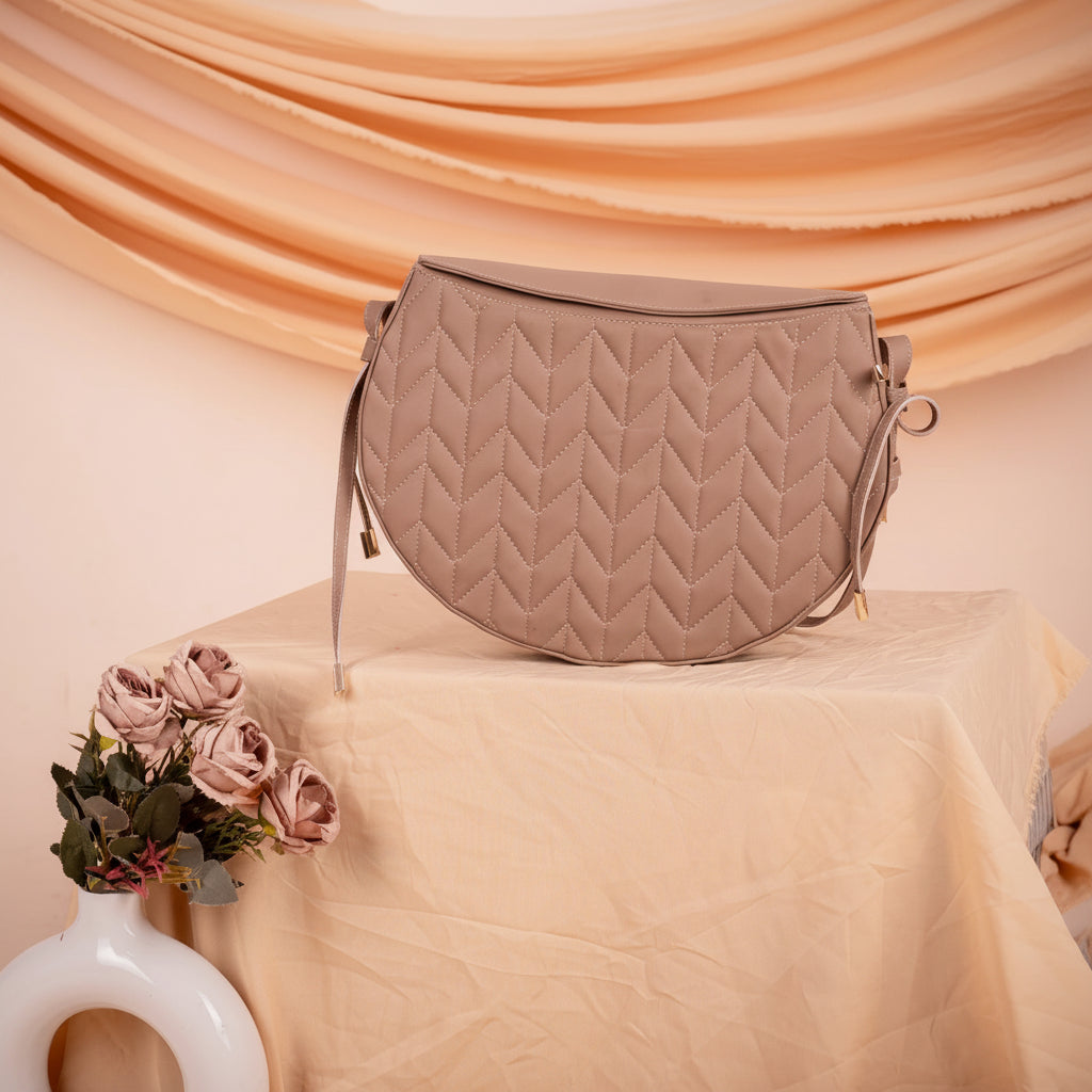 Quilted vegan leather handbag for women on a peach-colored surface with draped fabric in the background