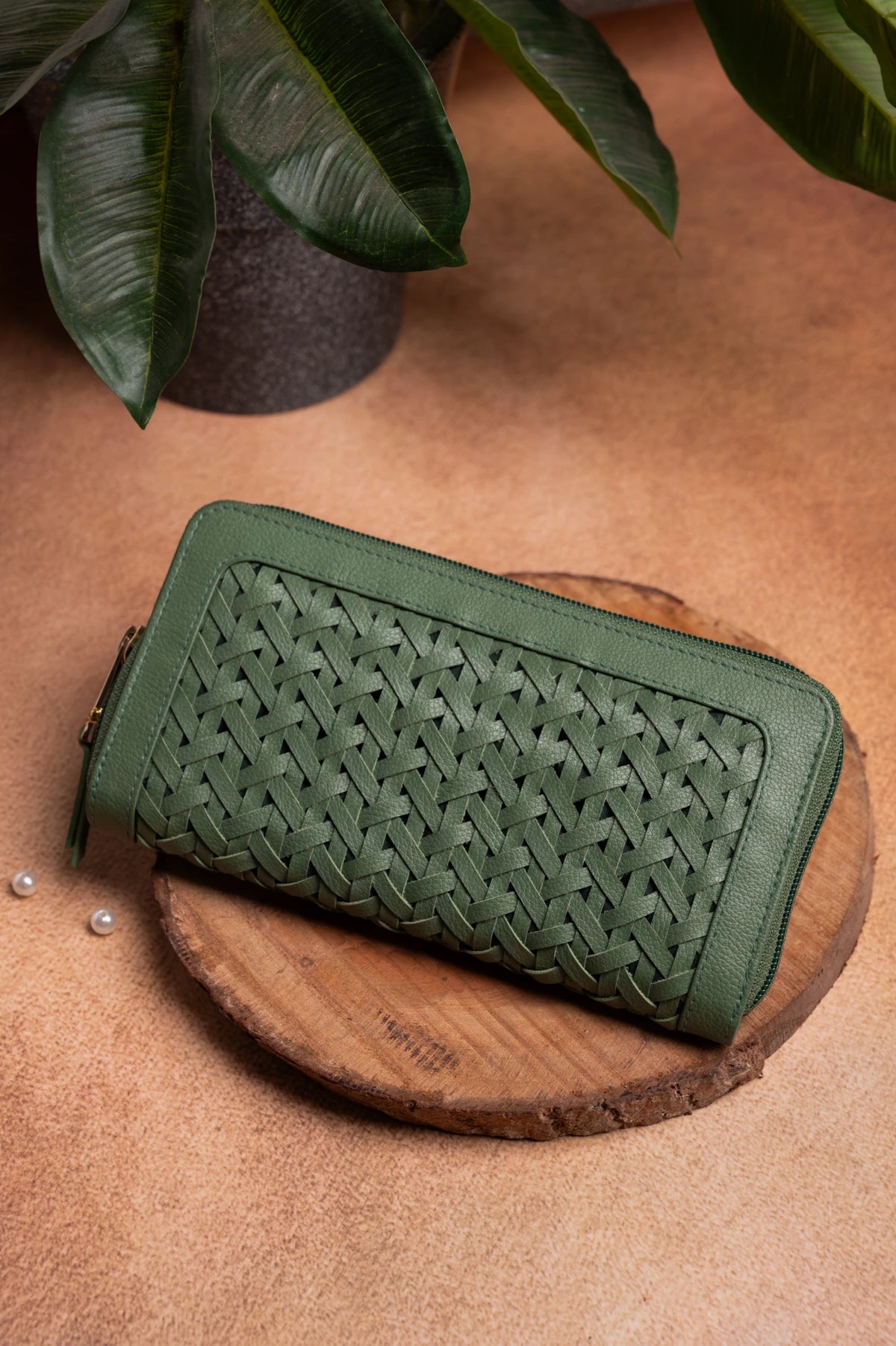 Green woven vegan leather wallet for women on a wooden surface with a plant in the background