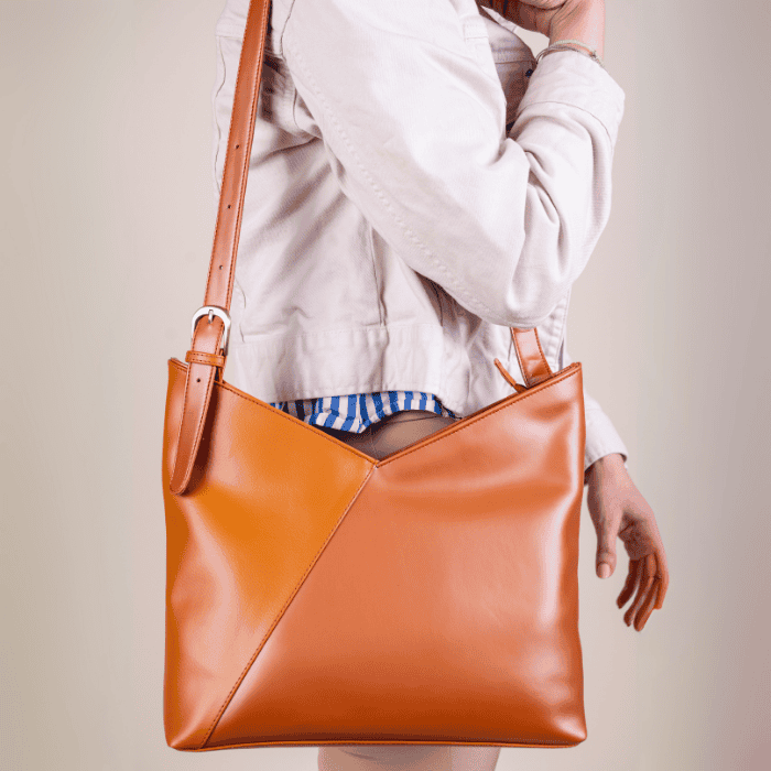 Person holding an orange vegan leather handbag for women with a plain background
