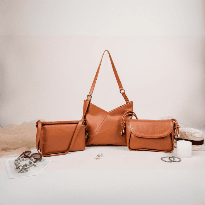 Three brown vegan leather handbags for women on a light surface with a neutral background