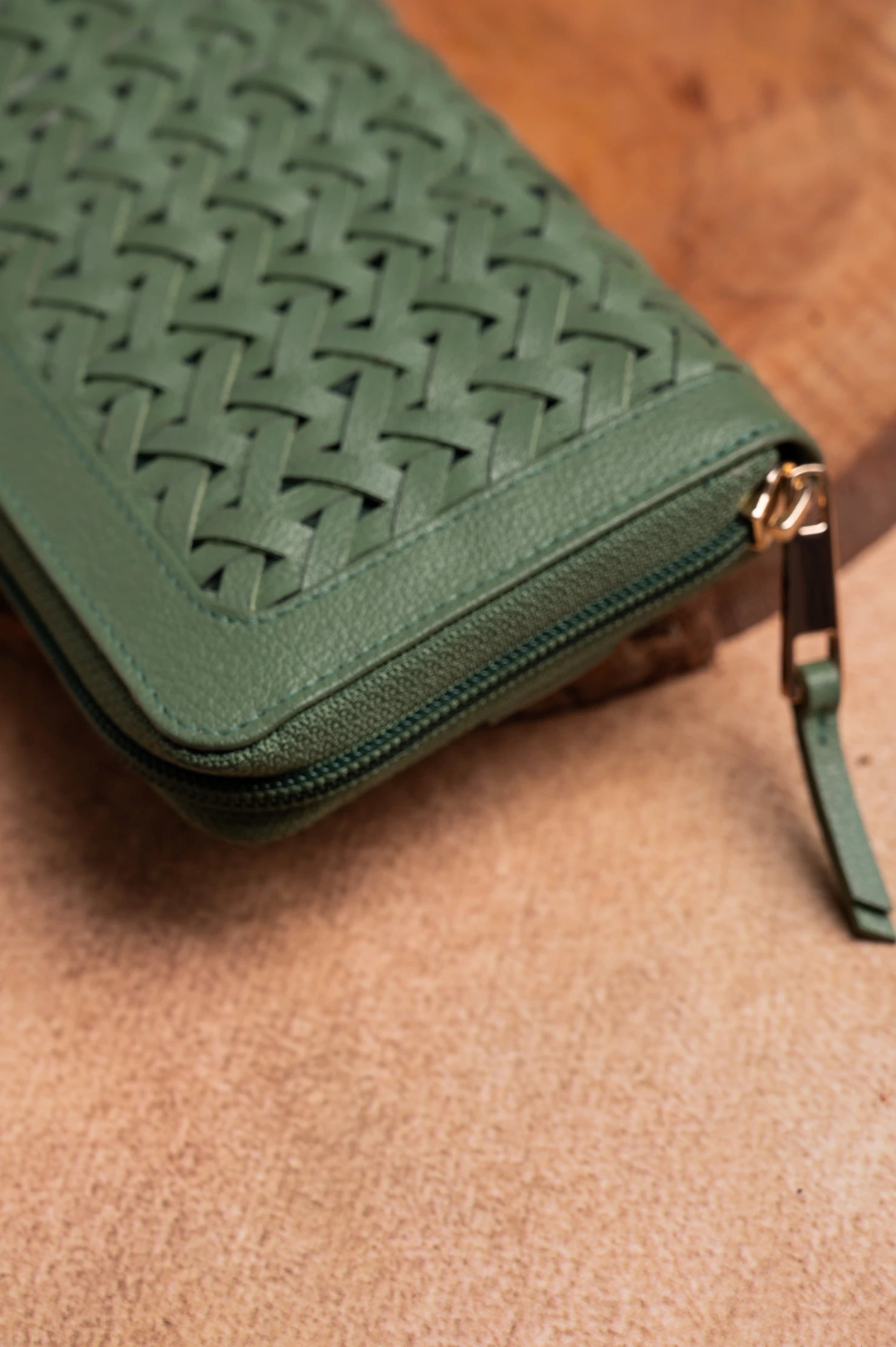 Green woven vegan leather clutch bag for women on a brown surface