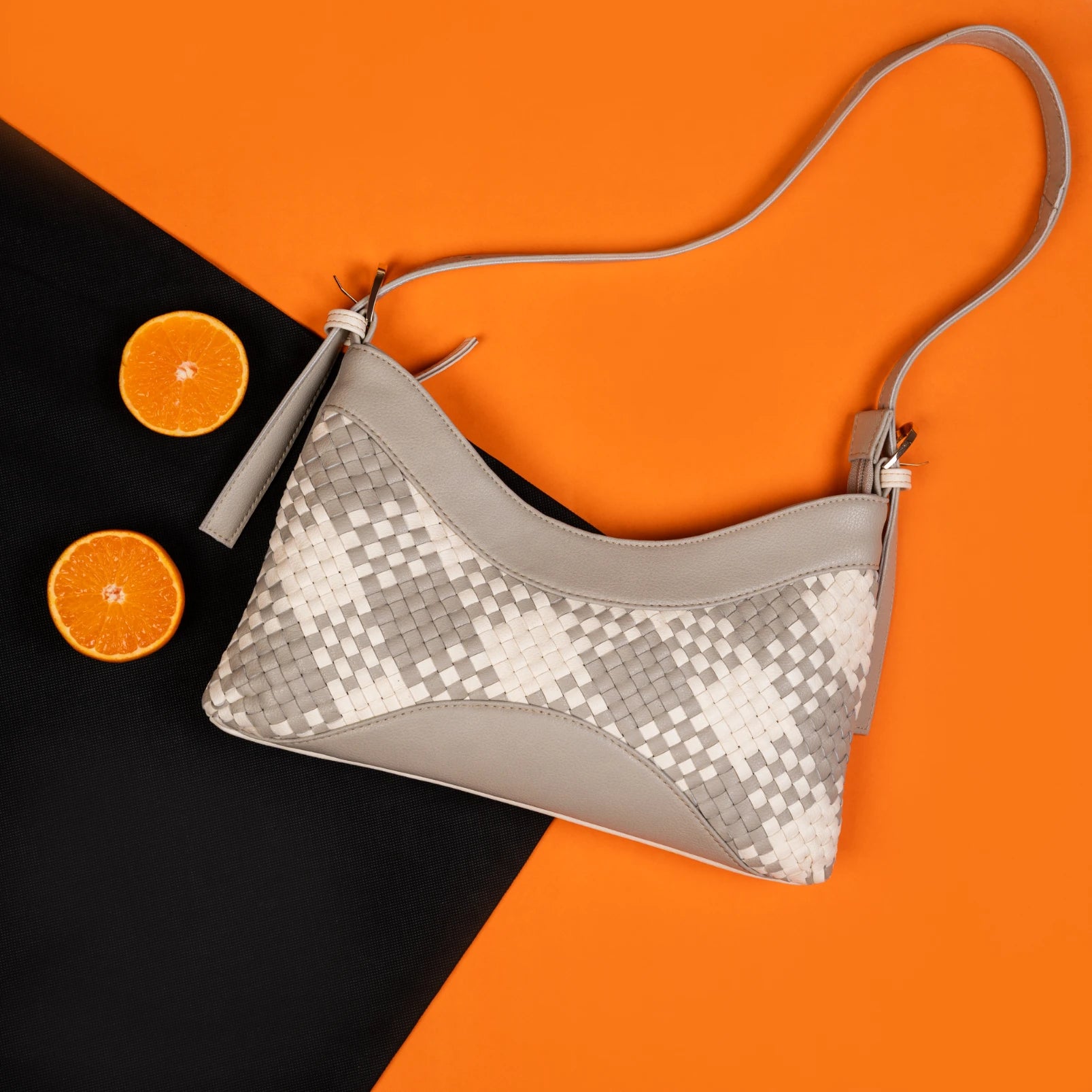 Gray vegan leather handbag for women with woven pattern on a black and orange background