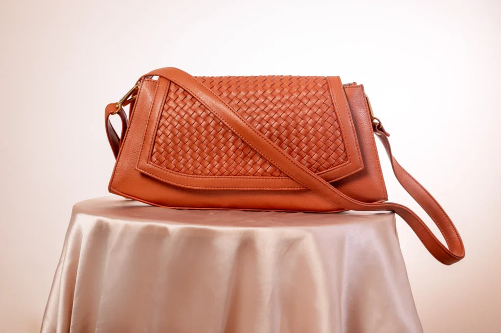 Brown woven vegan leather handbag for women on a beige tablecloth with a beige background