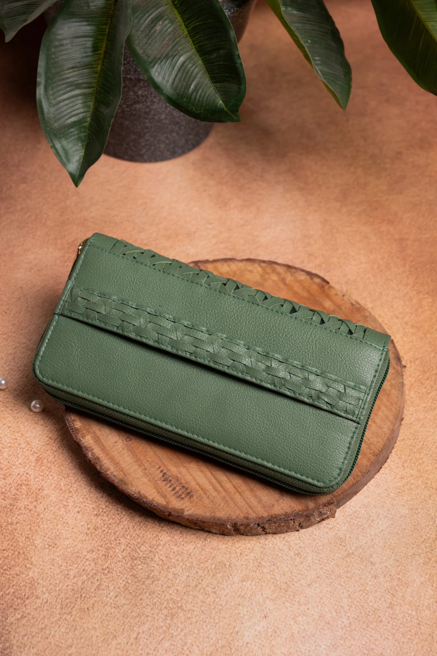 Green vegan leather wallet for women on a wooden surface with a plant in the background