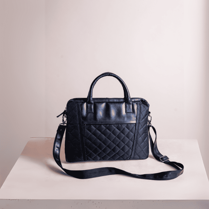 Black quilted vegan leather laptop bag on a white surface with a light gray background